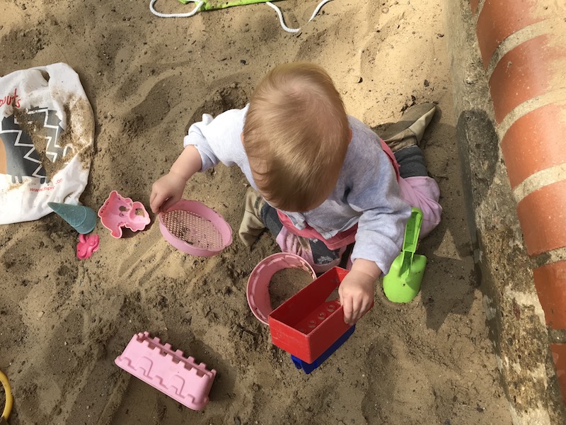 Alltag: Sandkasten, Kleinkind und Spielzeug