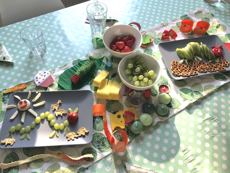 Gesunde Obstteller zur Raupe Nimmersatt Party: Raupen aus Trauben, Erdbeeren und Äpfeln neben selbstgemachter Deko und Kerzen-Raupe. | Mehr Infos zum Kindergeburtstag auf Mamaskind.de