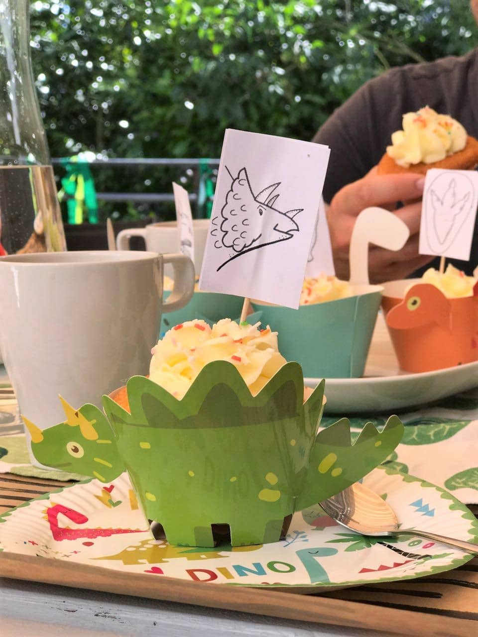 Perfekter Cupcake: Muffin mit Zitronen-Frischkäse-Frosting, Zuckerstreuseln und Dinosaurier-Banderole. - Mehr Infos zur Dino-Party auf Mamaskind.de