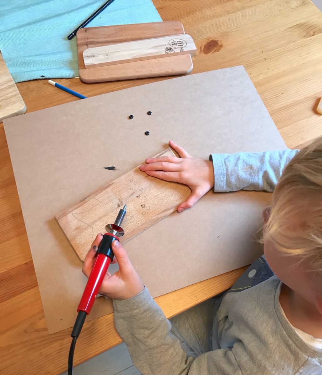 Der 5-Jährige brennt kleine Herzen und einen Stern in sein Brett. - Holz gravieren macht Spaß mit Kindern! Mehr Infos auf Mamaskind.de