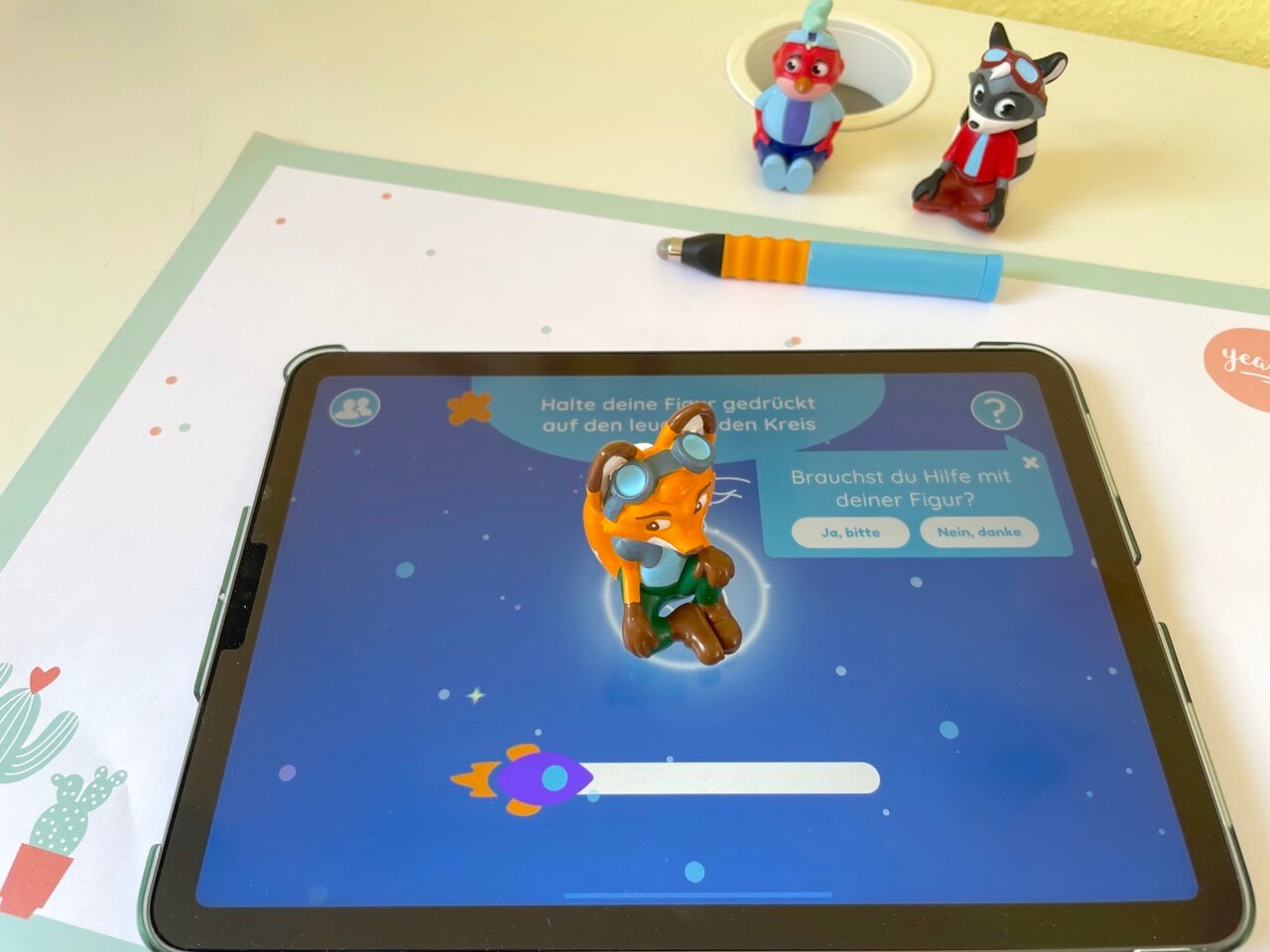 Edurino auf einem iOS-Apple-Tablet. Die Figur Mika startet die Deutsch-Lernspiele - bitte.kaufen