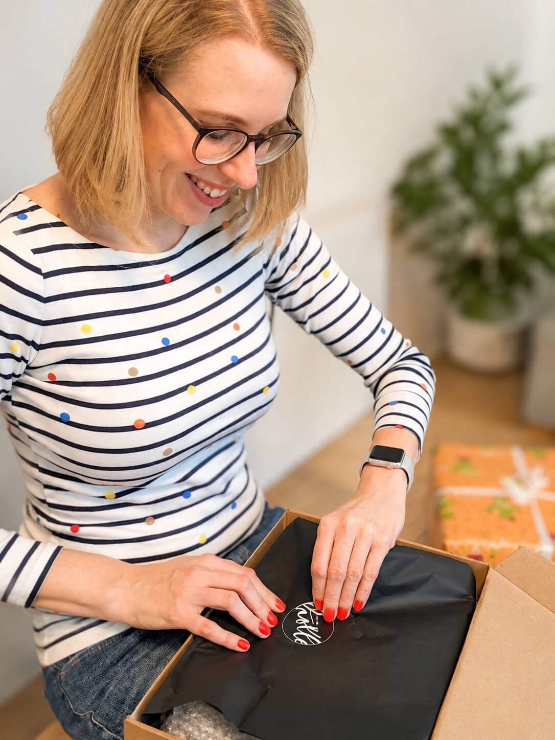 Sarah Depold, Gründerin von bitte.kaufen, packt ein Geschenk aus